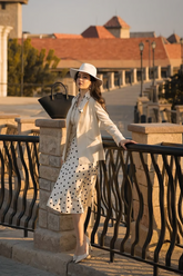a lady in a polka dot shirt, a white vest, a polka dot skirt and a white blazer